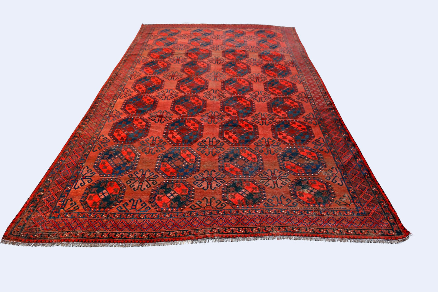 An antique handmade Afghan Turkmen rug featuring a repeating octagonal pattern in red and blue.