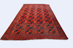 An antique handmade Afghan Turkmen rug featuring a repeating octagonal pattern in red and blue.