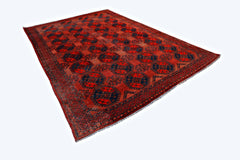 An antique Afghan Turkmen rug featuring a repeating octagonal gul pattern in red and blue tones.