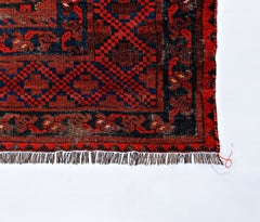 An antique Afghan Turkmen rug featuring a geometric red and blue pattern with a fringed edge.