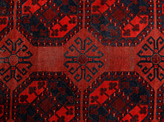 An antique Afghan Turkmen rug featuring a repeating geometric pattern in deep red and black.