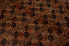 An antique Afghan Turkmen rug featuring a repeating geometric pattern in earthy tones.
