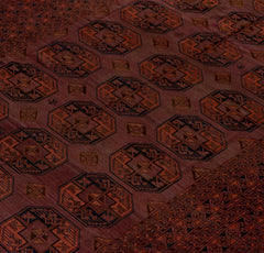 An antique Afghan Turkmen rug featuring repeating geometric octagonal motifs in red and blue wool.
