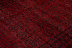 An antique Afghan Turkmen rug featuring a deep red field with repeating dark geometric motifs.