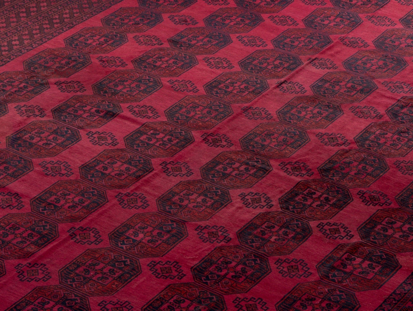 An antique Afghan Turkmen rug featuring a repeating geometric octagonal pattern in deep red tones.