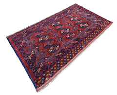 Antique Turkmen Tekke rug in deep red with repeating dark blue gul motifs, geometric borders, and a short white fringe.
