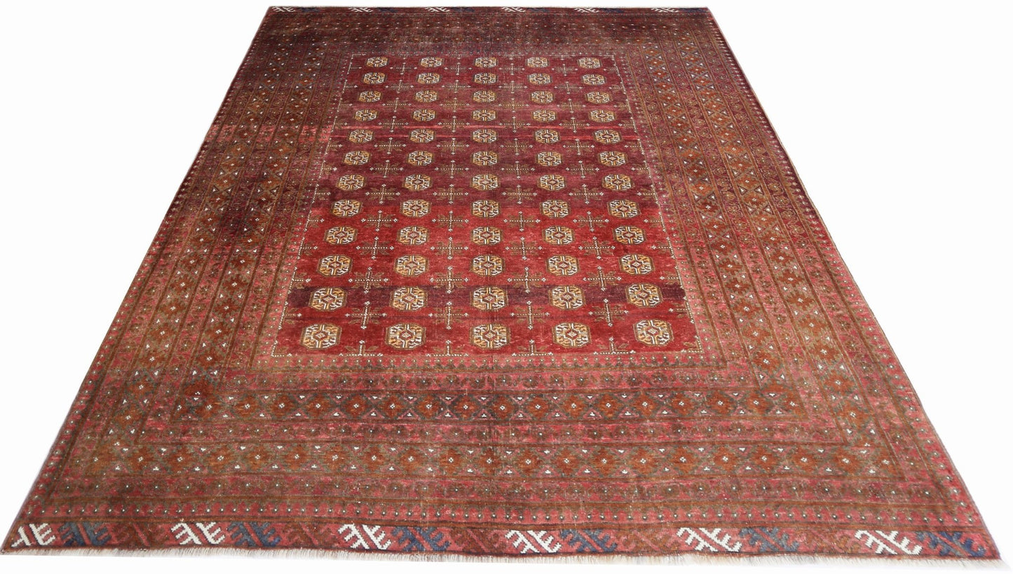 An antique Afghan Turkmen rug featuring a deep red field with repeating geometric gul motifs.