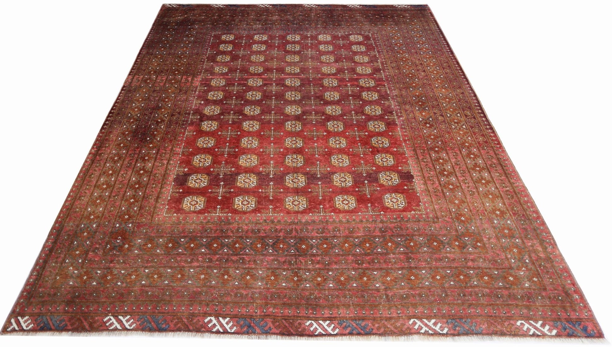 An antique Afghan Turkmen rug featuring a deep red field with repeating geometric gul motifs.