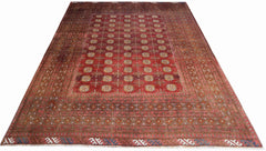 An antique Afghan Turkmen rug featuring a deep red field with repeating geometric gul motifs.
