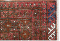 A handwoven antique Turkmen rug featuring geometric patterns in deep red, blue, and ivory wool.