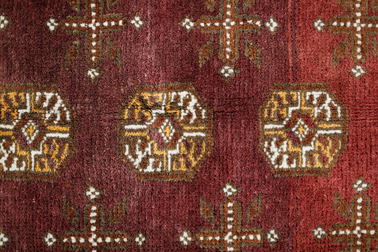 Handwoven Afghan Turkmen rug featuring geometric octagonal medallions on a deep red wool field.