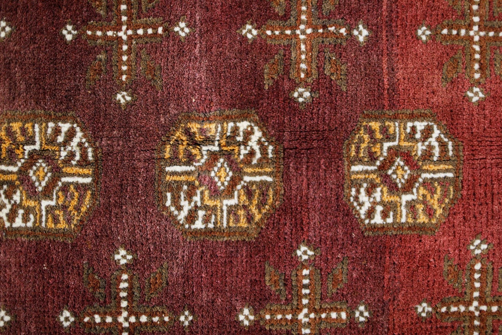 Handwoven Afghan Turkmen rug featuring geometric octagonal medallions on a deep red wool field.