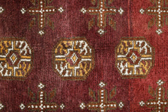 Handwoven Afghan Turkmen rug featuring geometric octagonal medallions on a deep red wool field.