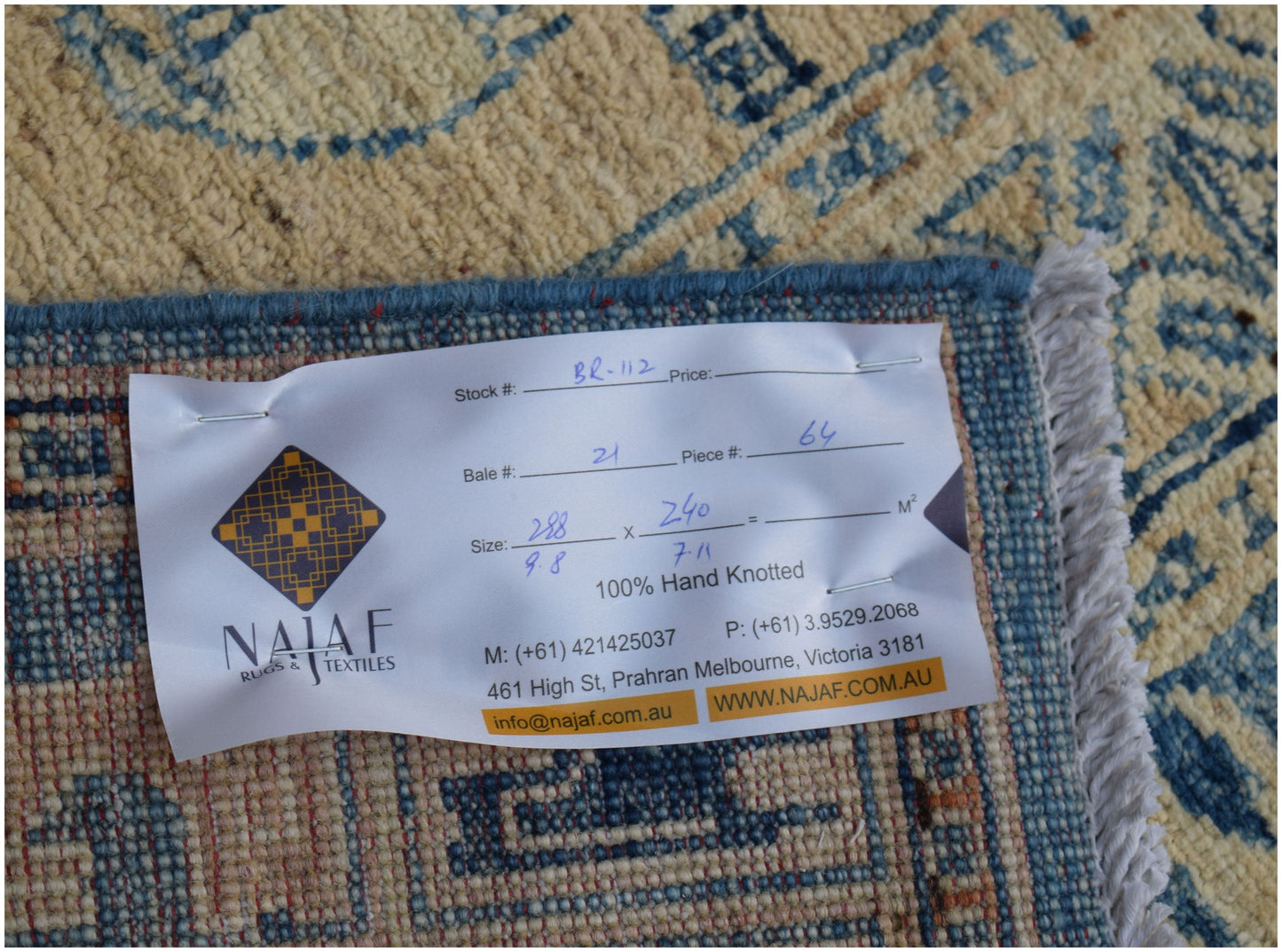 A close-up view of the back of a handmade Afghan Chobi rug with a product information label.