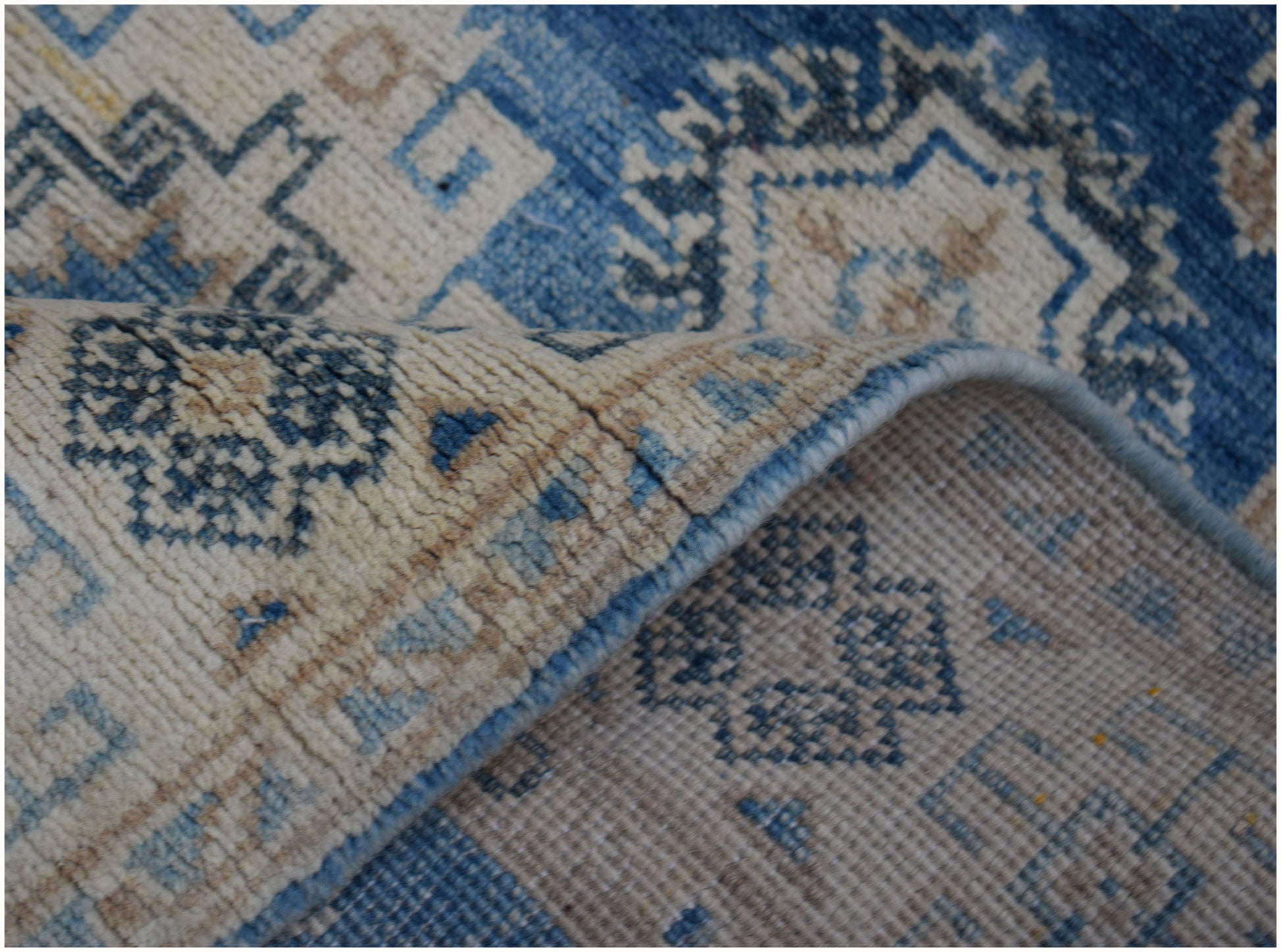 A handmade Afghan Kazakh runner featuring a geometric pattern in shades of blue and beige.
