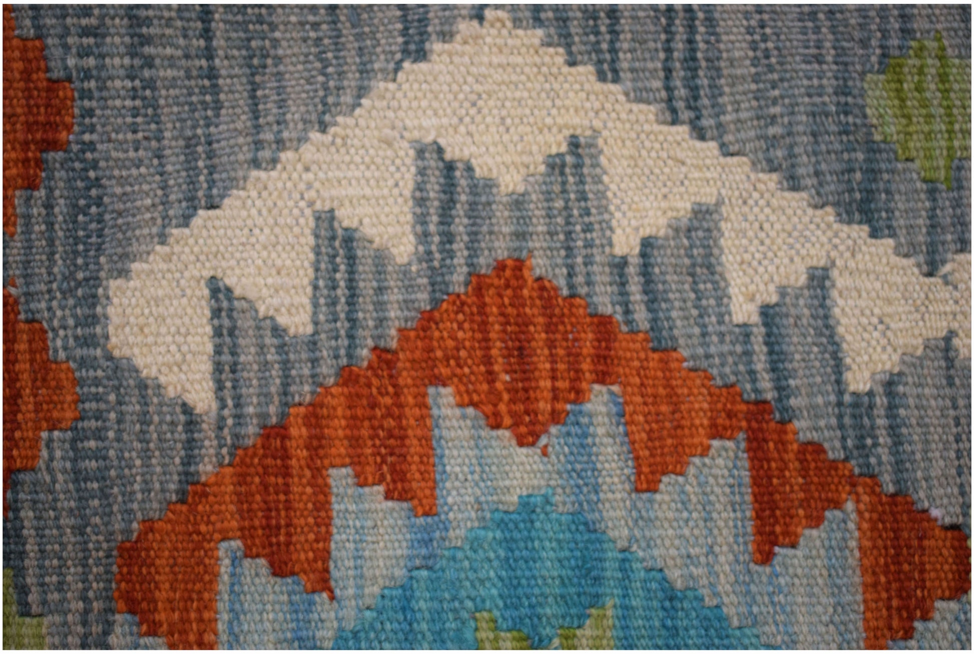 A close-up of a handmade Afghan Maimana kilim runner featuring geometric patterns in wool.
