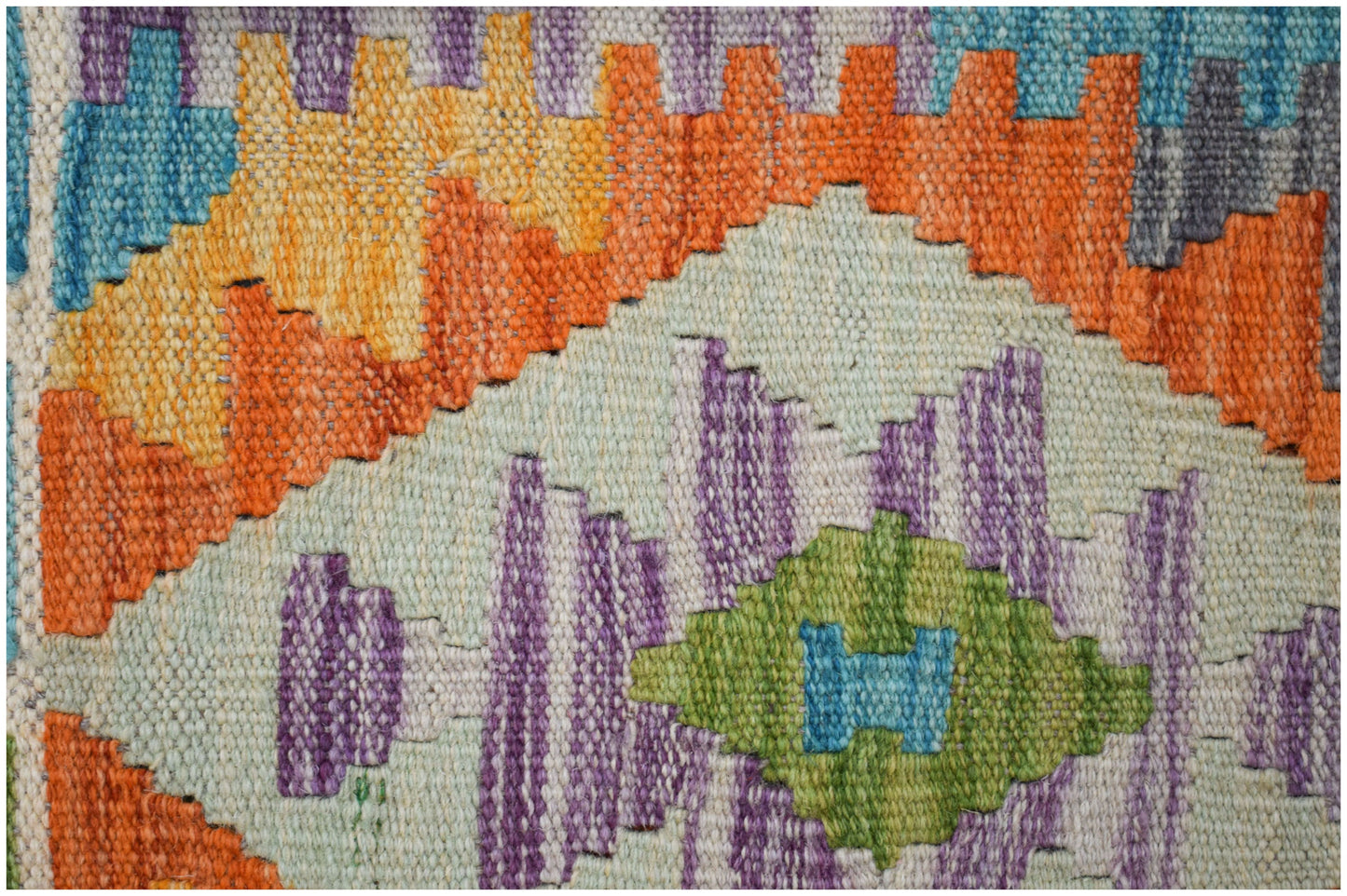 A close-up of a handmade Afghan Maimana kilim runner featuring geometric patterns in vibrant colors.