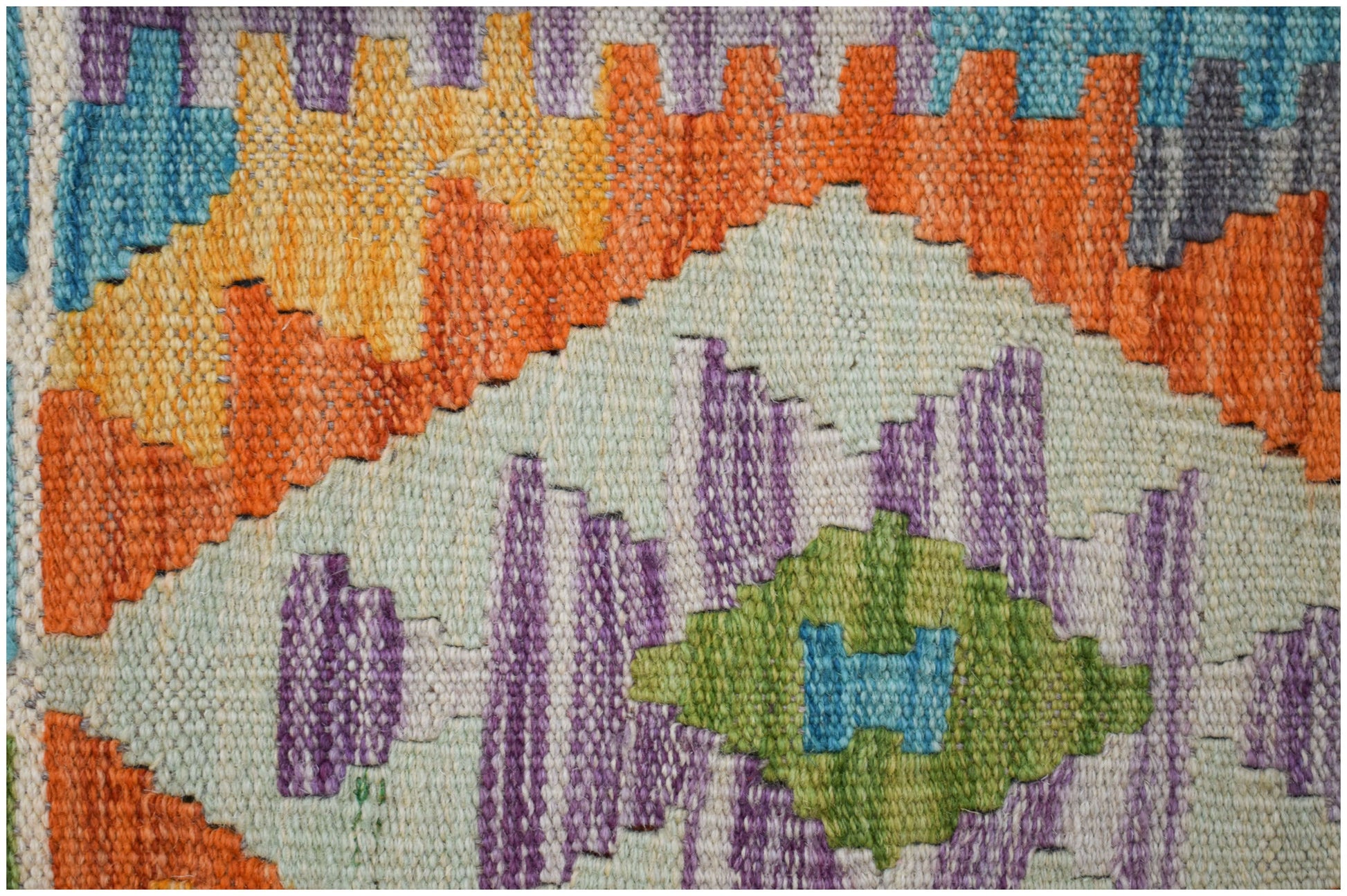 A close-up of a handmade Afghan Maimana kilim runner featuring geometric patterns in vibrant colors.