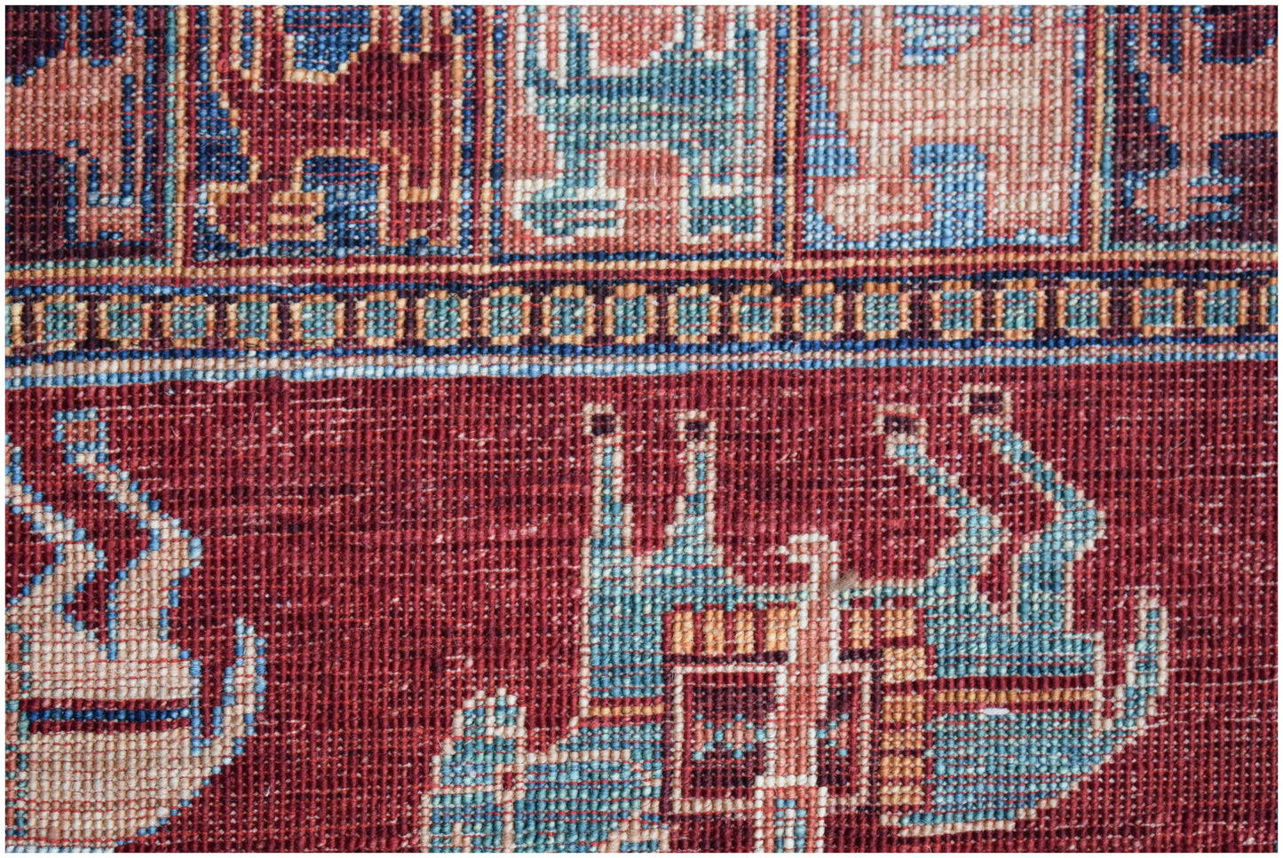 A close-up of a handwoven Afghan Chobi rug featuring intricate geometric and animal motifs.