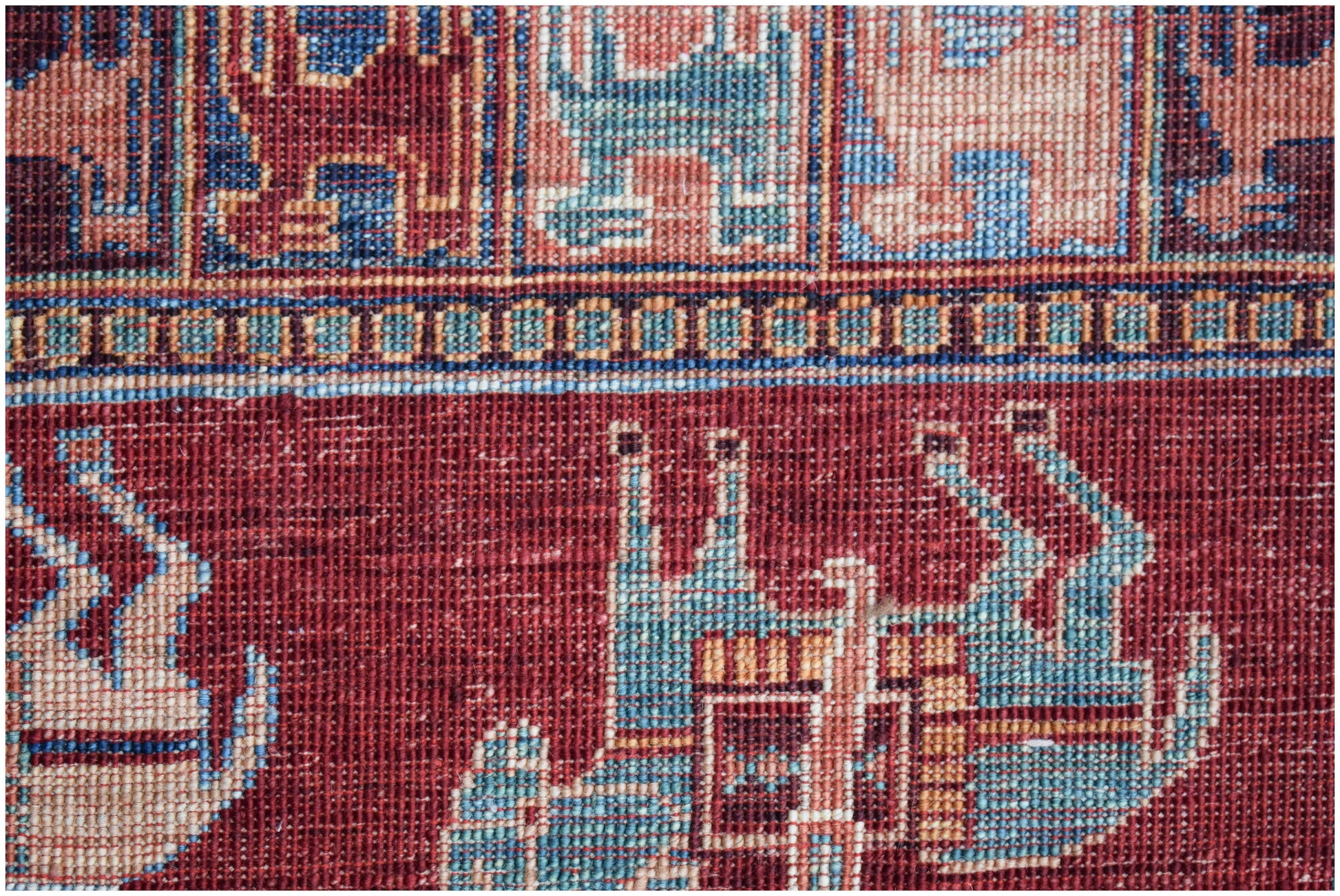A close-up of a handwoven Afghan Chobi rug featuring intricate geometric and animal motifs.