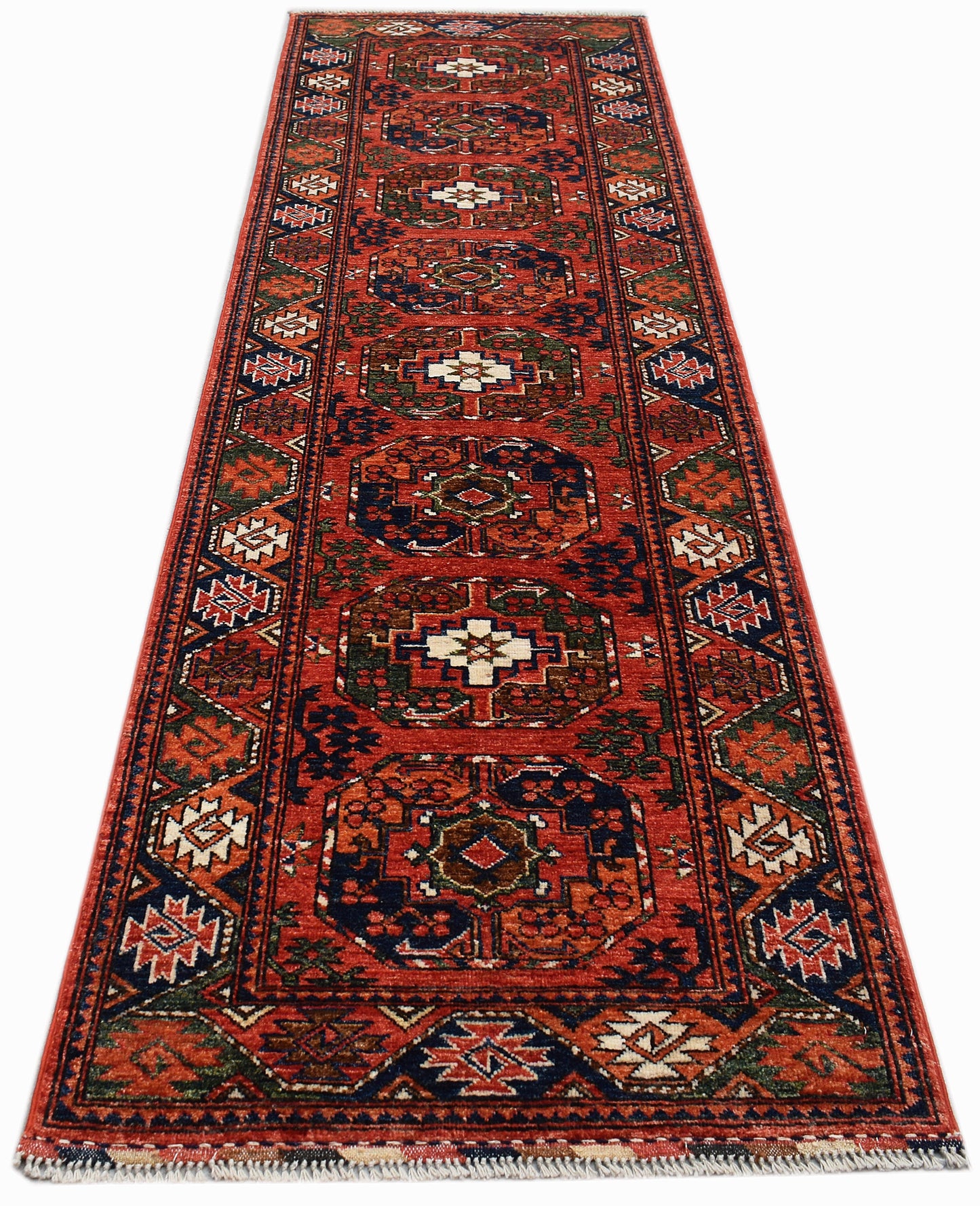A handmade Afghan Chobi runner rug featuring traditional geometric patterns in red, blue, and cream.