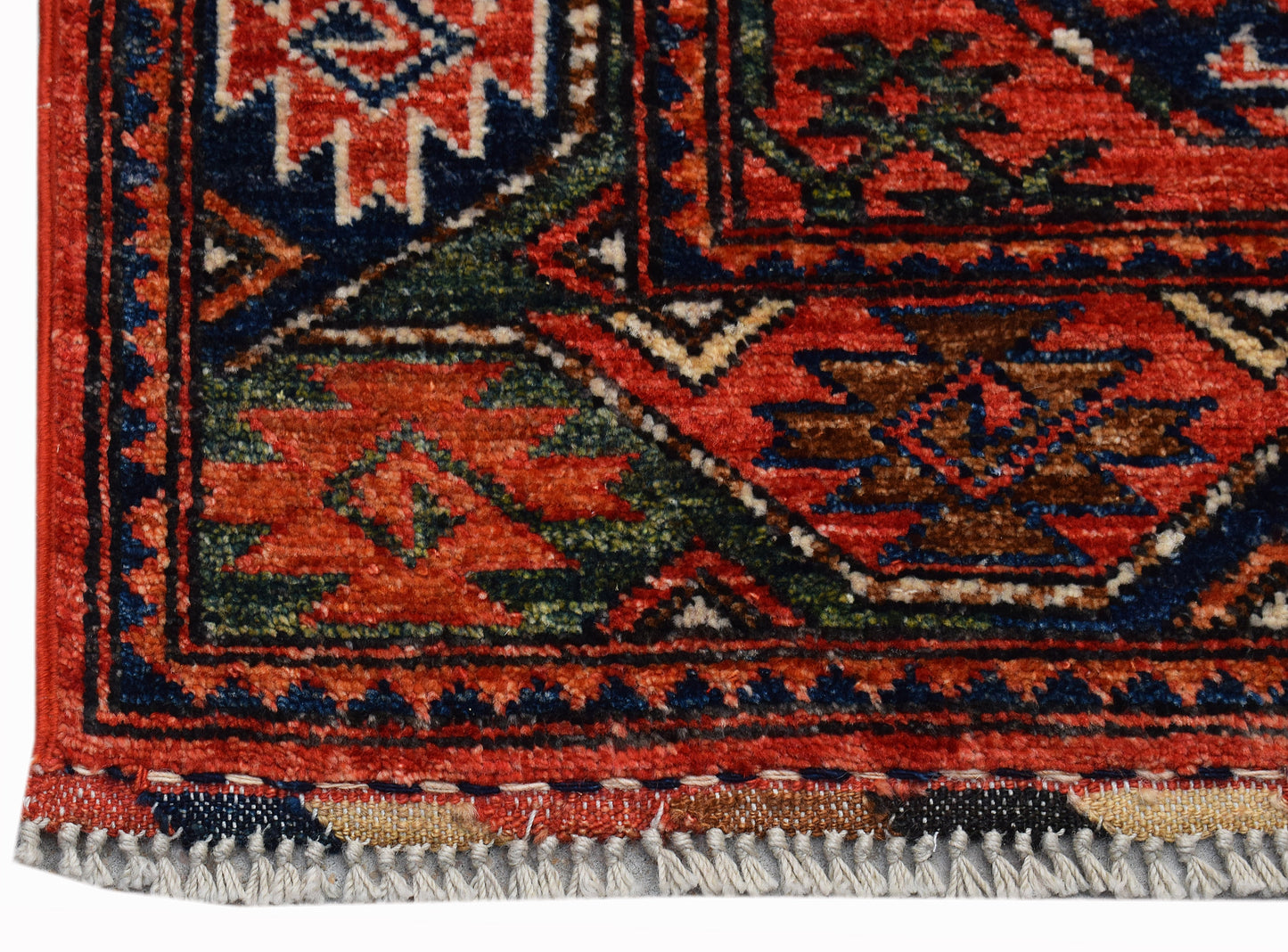 A close-up of a handwoven Afghan Chobi runner featuring intricate geometric patterns in red and blue.