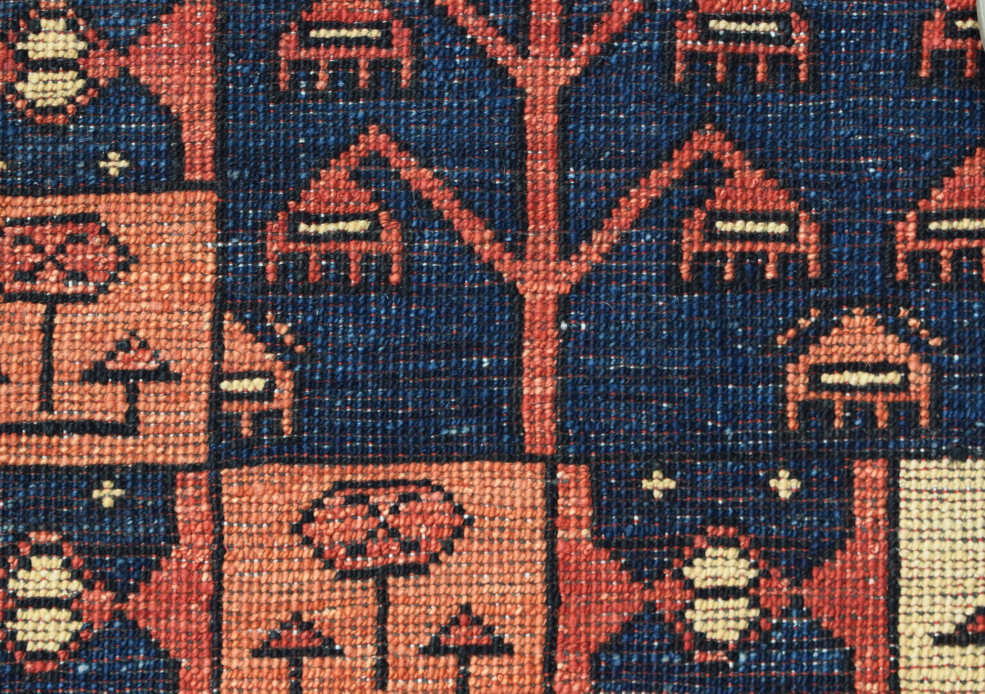 A close-up of a handwoven Afghan Chobi rug featuring geometric tree and floral motifs in wool.