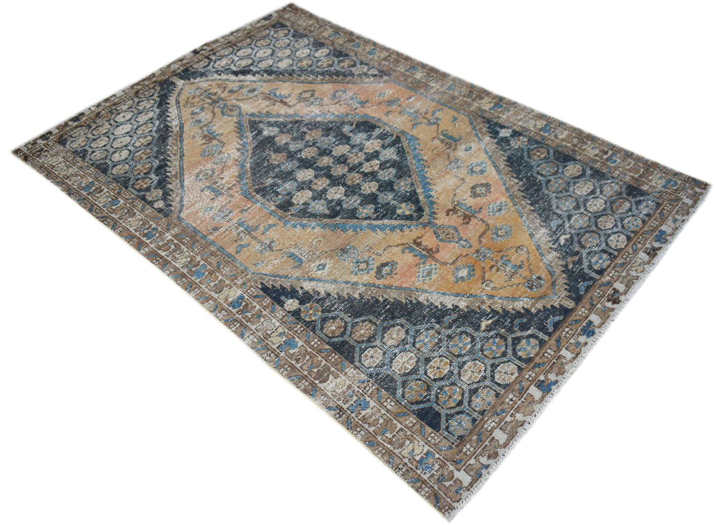 A vintage Persian rug featuring a central diamond medallion in blue and tan with geometric patterns.