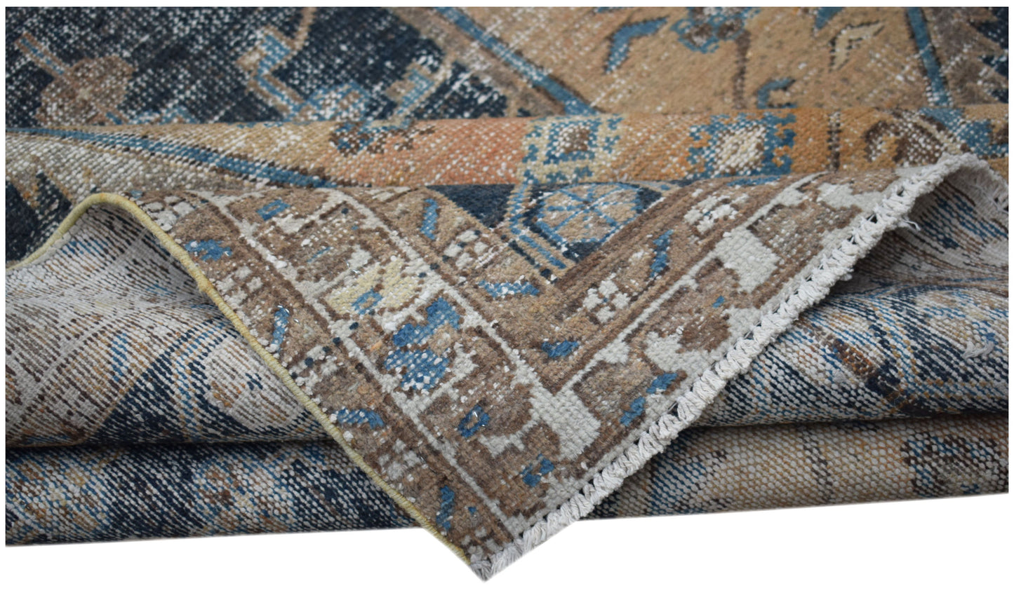 A folded vintage Persian rug featuring intricate blue and tan geometric patterns on wool.