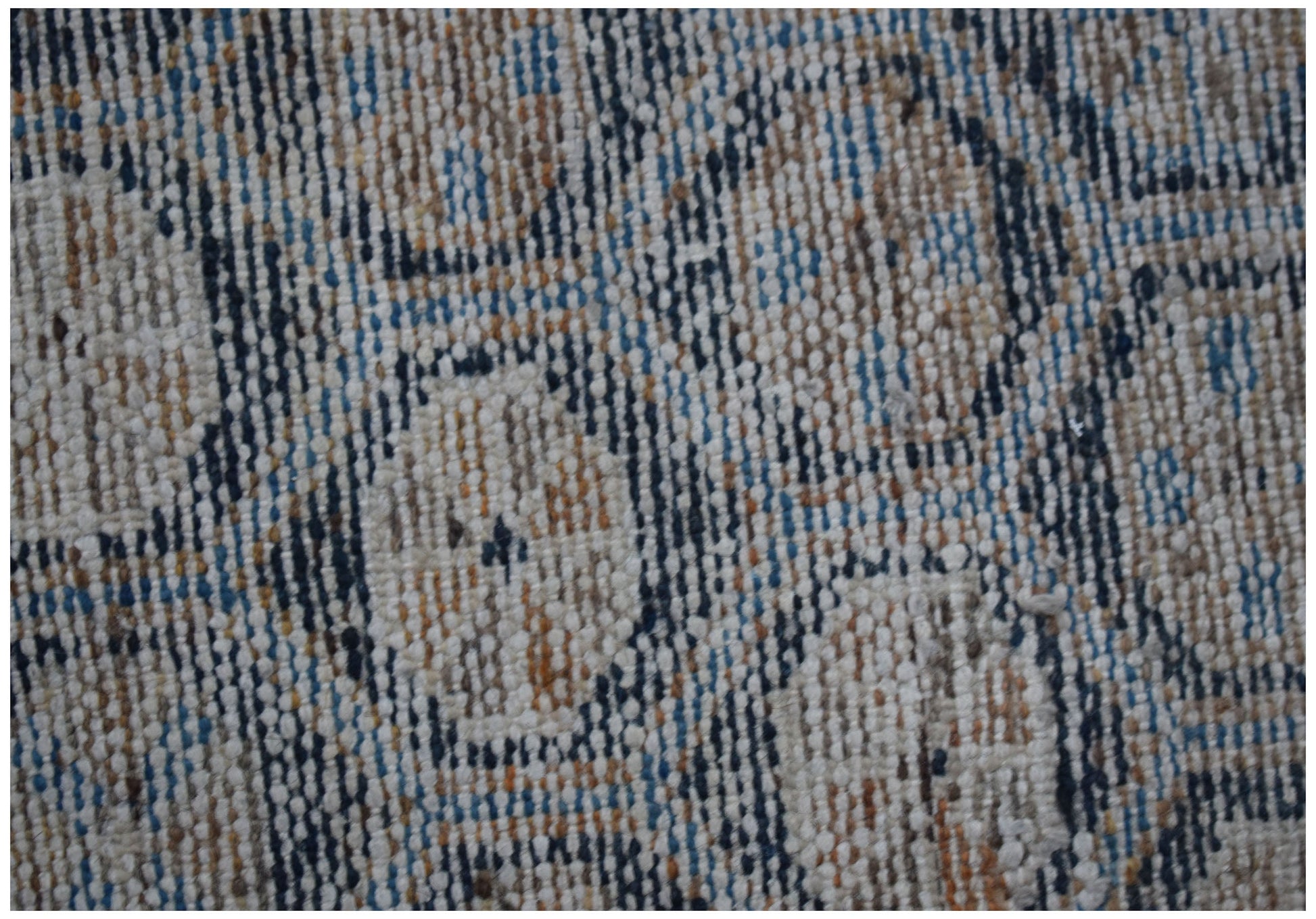 A close-up view of a vintage Persian rug featuring a faded geometric pattern in blue and tan.