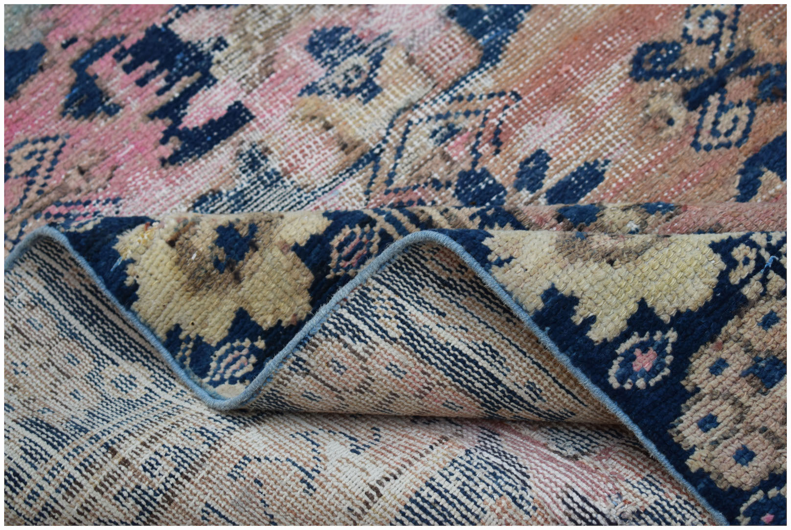 A vintage handwoven Persian runner featuring a faded floral pattern in blue, pink, and beige.