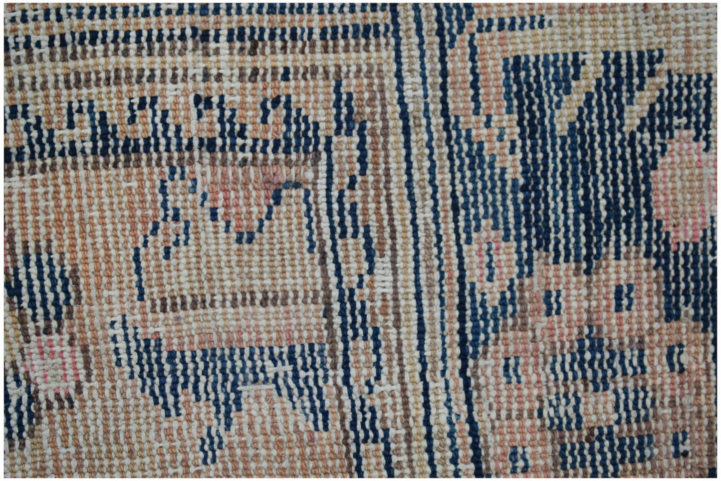 A close-up of a vintage Persian runner featuring a handwoven geometric pattern in blue and tan.