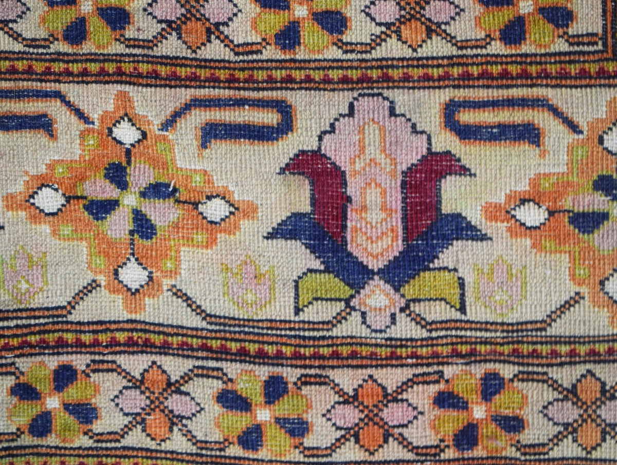 A close-up of a hand-knotted Afghan rug featuring intricate floral and geometric patterns.