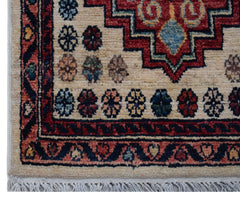 A handmade Afghan Chobi rug featuring a geometric red medallion on a cream field with fringe.