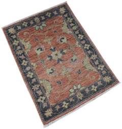 A handmade Afghan Chobi rug featuring a floral pattern in rust, sage green, and charcoal grey.