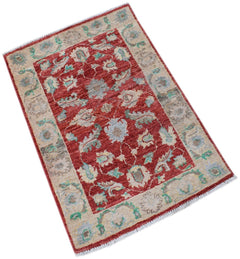 A handmade Afghan Chobi rug featuring a floral pattern in red, beige, and soft blue tones.