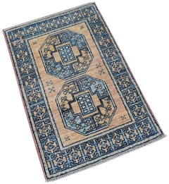A handmade Afghan Chobi rug featuring two blue geometric medallions on a tan wool field.
