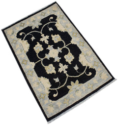 A handmade Afghan Chobi rug featuring a black central field with floral patterns and a light border.