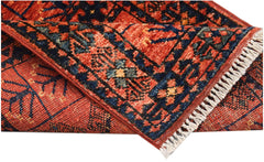 A folded handmade Afghan Chobi rug featuring a traditional red and blue geometric pattern.