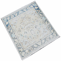 A mini vintage Persian Kerman rug featuring a central medallion and floral motifs in blue and cream.