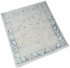 A mini vintage Persian Kerman rug featuring a central medallion in soft blue and cream tones.