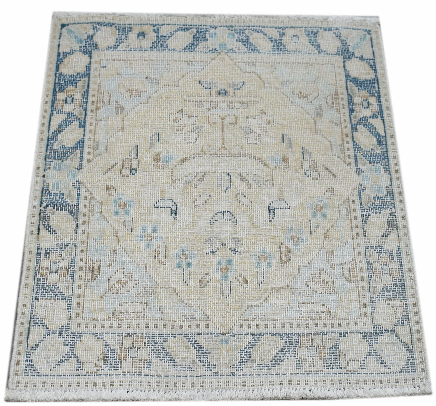 A mini vintage Persian Kerman rug featuring a central medallion in soft blue and beige tones.