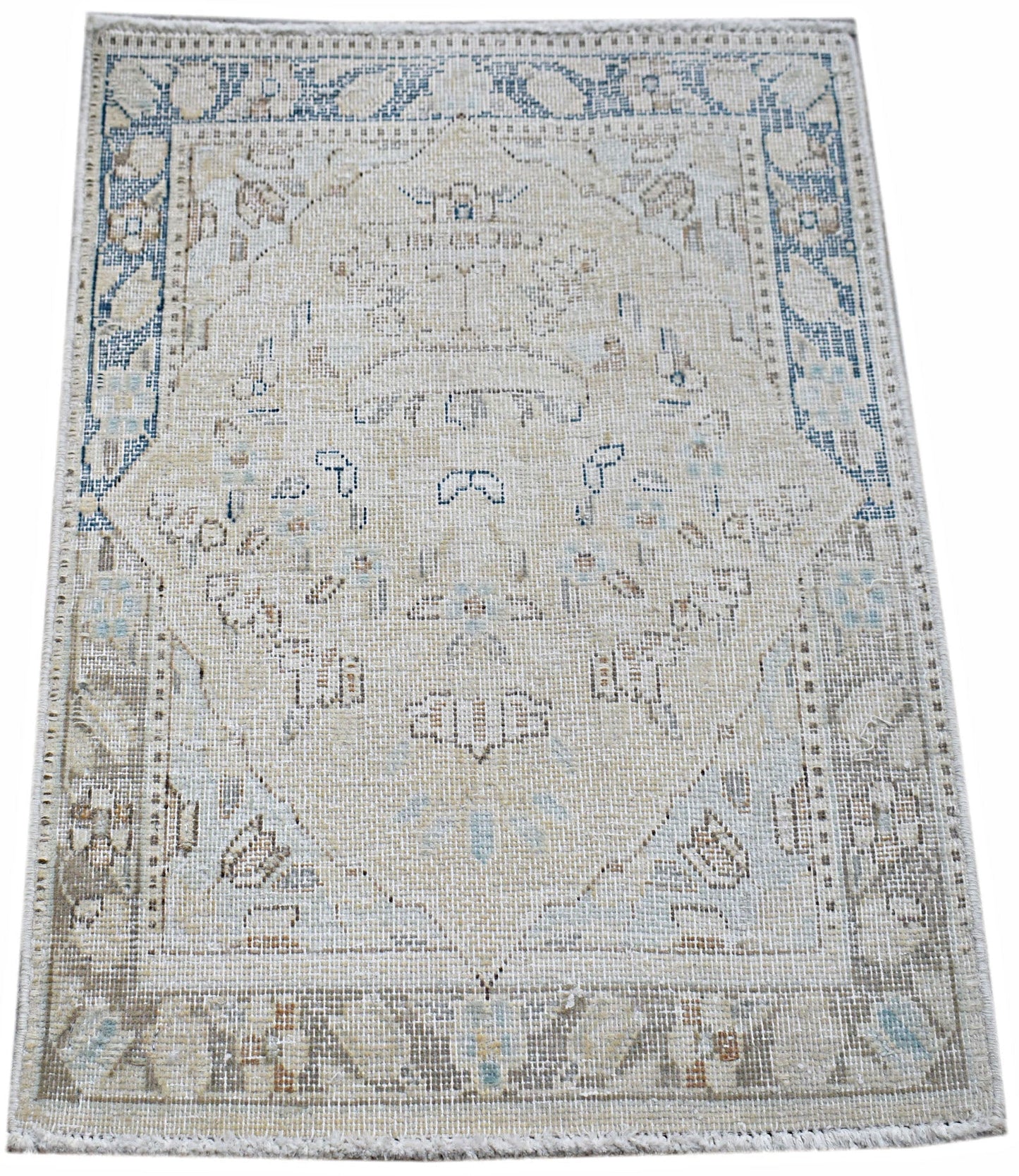 A mini vintage Persian Kerman rug featuring a central medallion and floral motifs in muted tones.