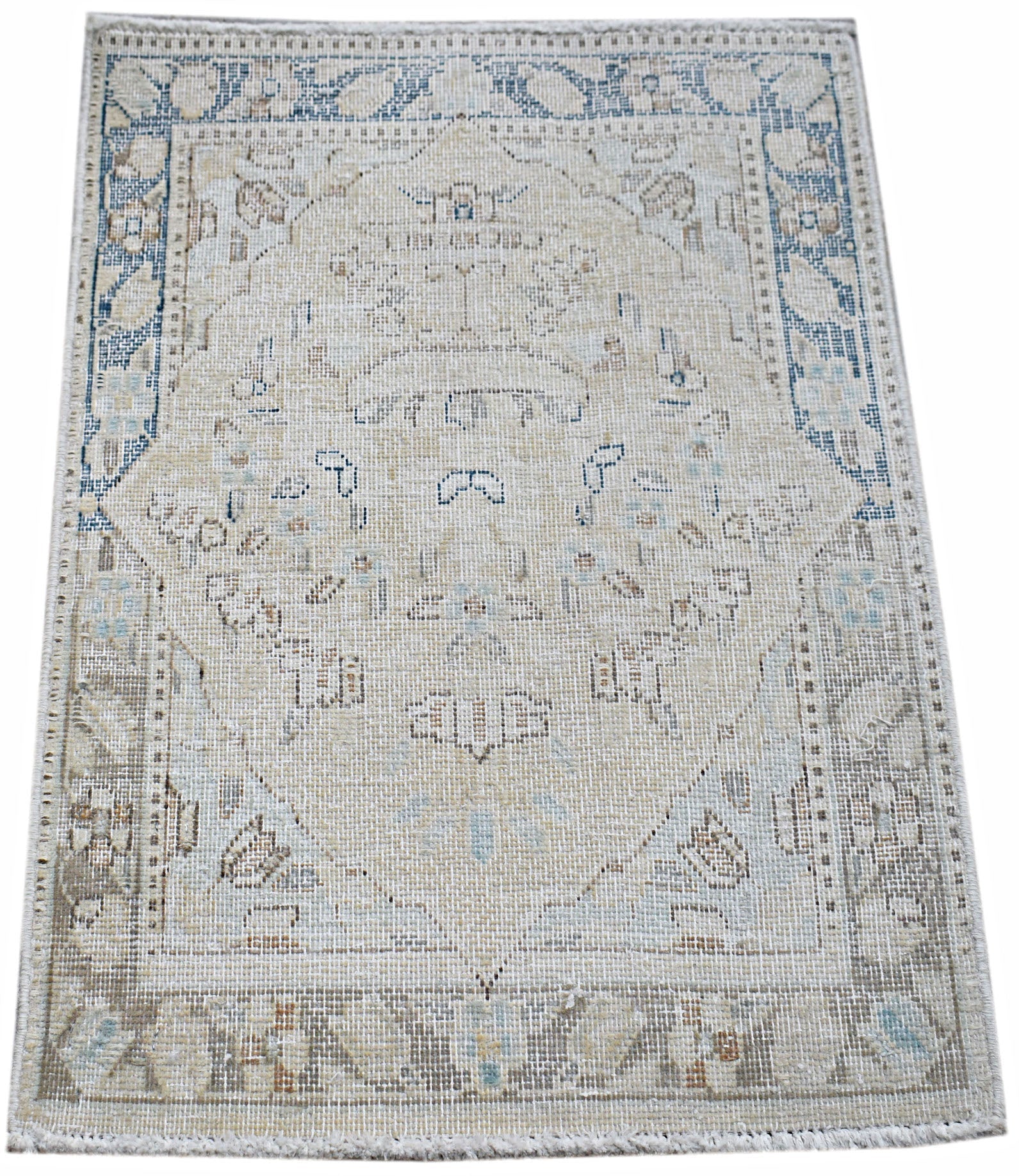 A mini vintage Persian Kerman rug featuring a central medallion and floral motifs in muted tones.