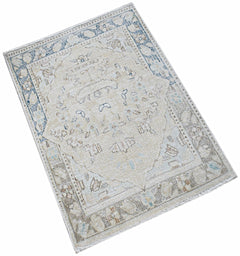 A mini vintage Persian Kerman rug featuring a central medallion and floral motifs in muted tones.