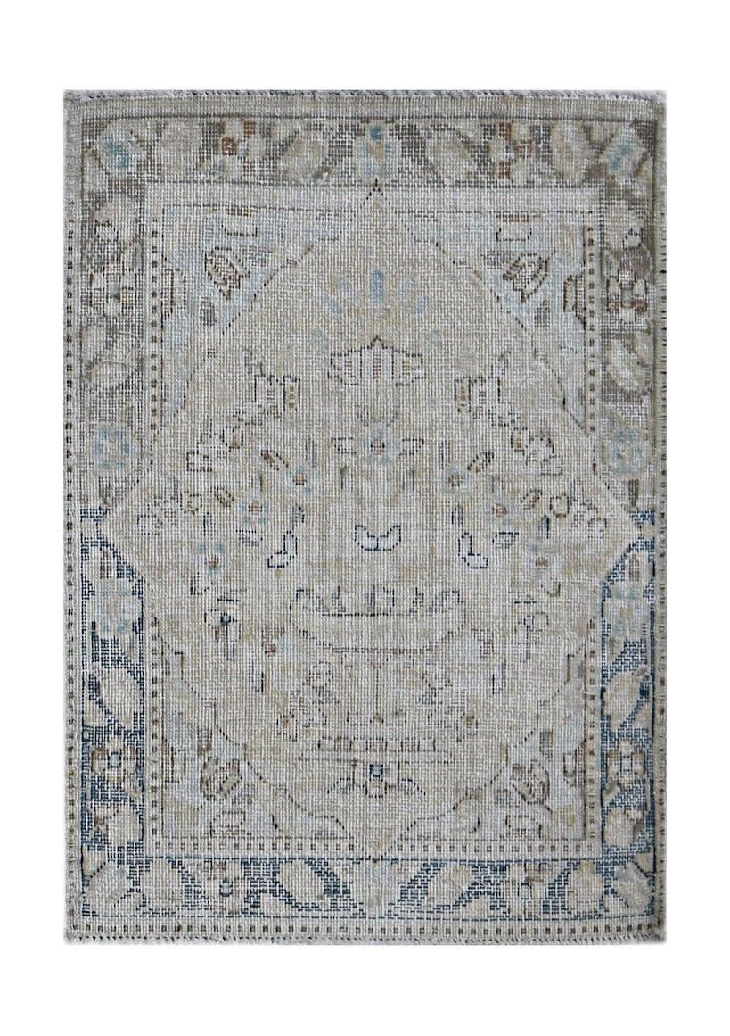 A mini vintage Persian Kerman rug featuring a central medallion in soft blue and beige tones.