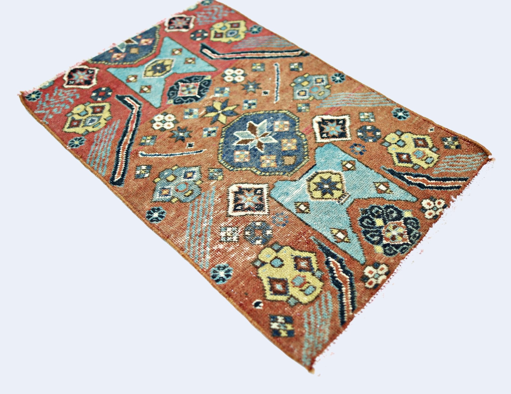 A small, rectangular vintage Persian rug featuring geometric patterns in blue, yellow, and red.