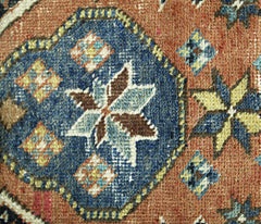 A close-up of a vintage Persian rug featuring a blue medallion with floral and geometric patterns.