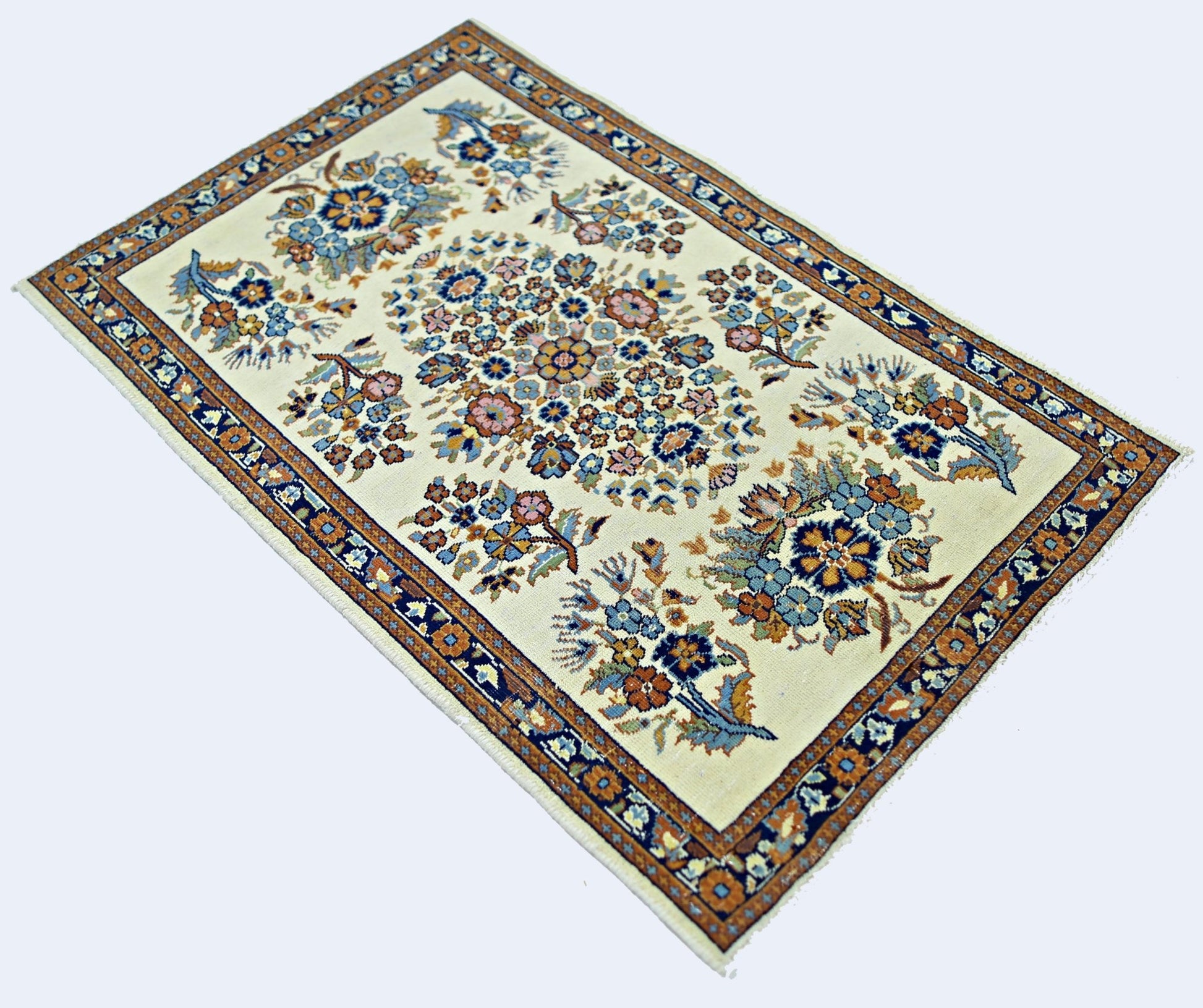 A handmade vintage Persian Sarouk rug featuring a floral pattern on a cream background.