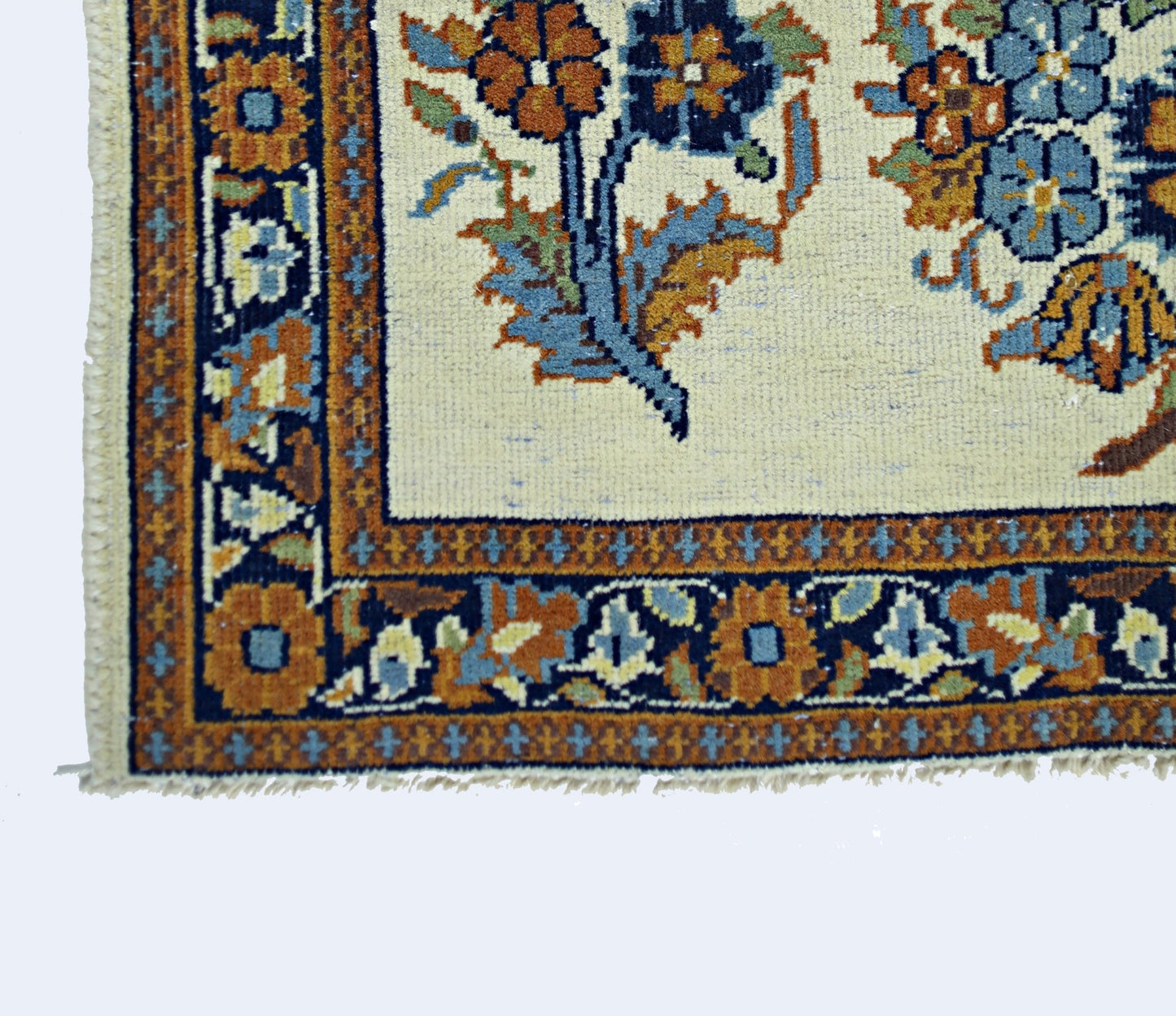A vintage Persian Sarouk rug featuring a floral pattern in blue and orange on a cream background.